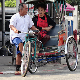 Paar unterhält sich auf dem Fahrrad und einer Ritscha auf der Strasse